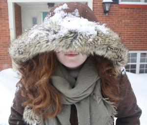 Ashley Favata photo: Katie McCafferty covers her face to protect it from the cold wind blowing around and the snow falling down on campus.